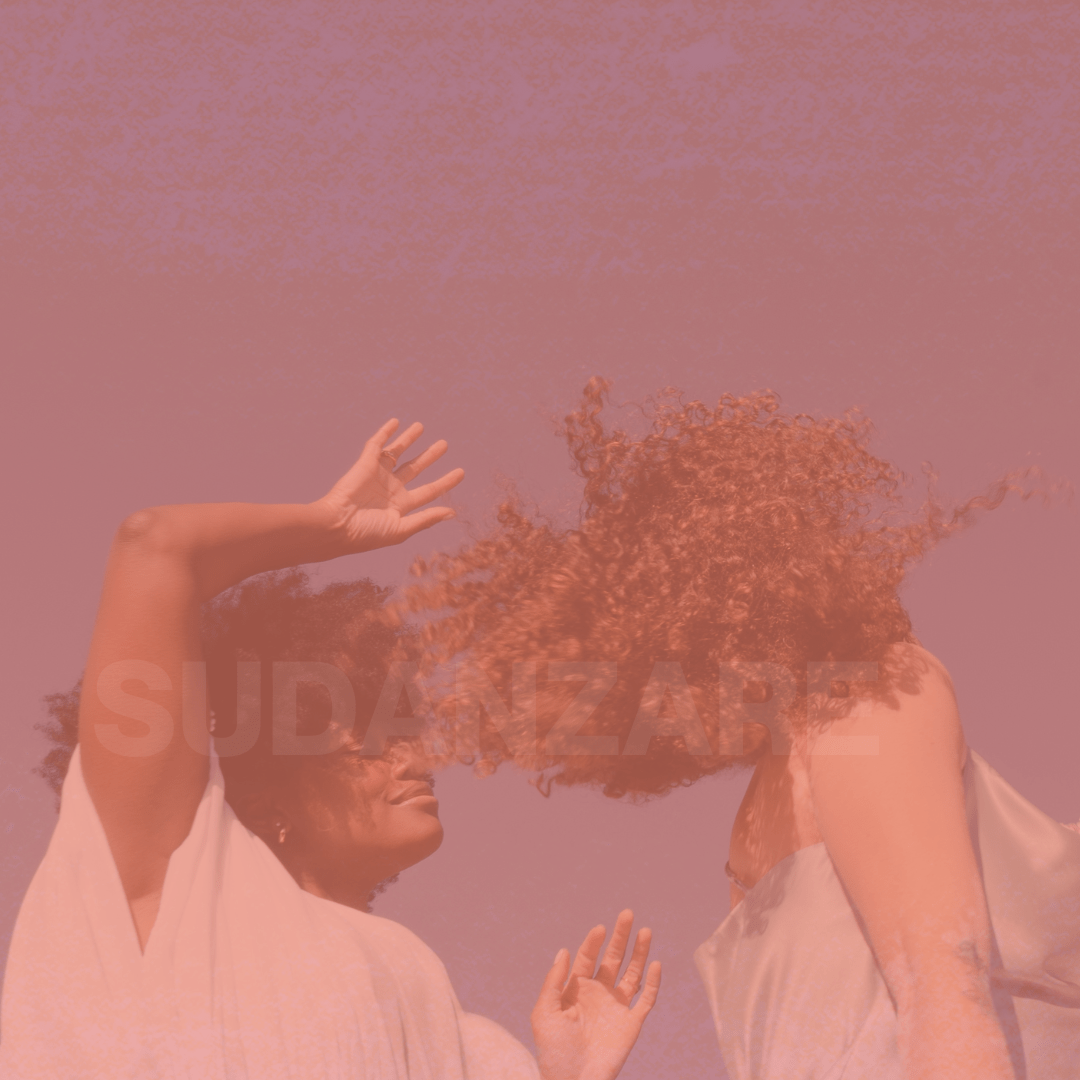 Due donne danzano con energia e capelli mossi in una luce calda e rosata, evocando il movimento e la passione della Pizzica. Immagine per corsi di danza contemporanea e popolare associazione sudanzare Ballo della Pizzica tarantella tammurriata dance danse taranta